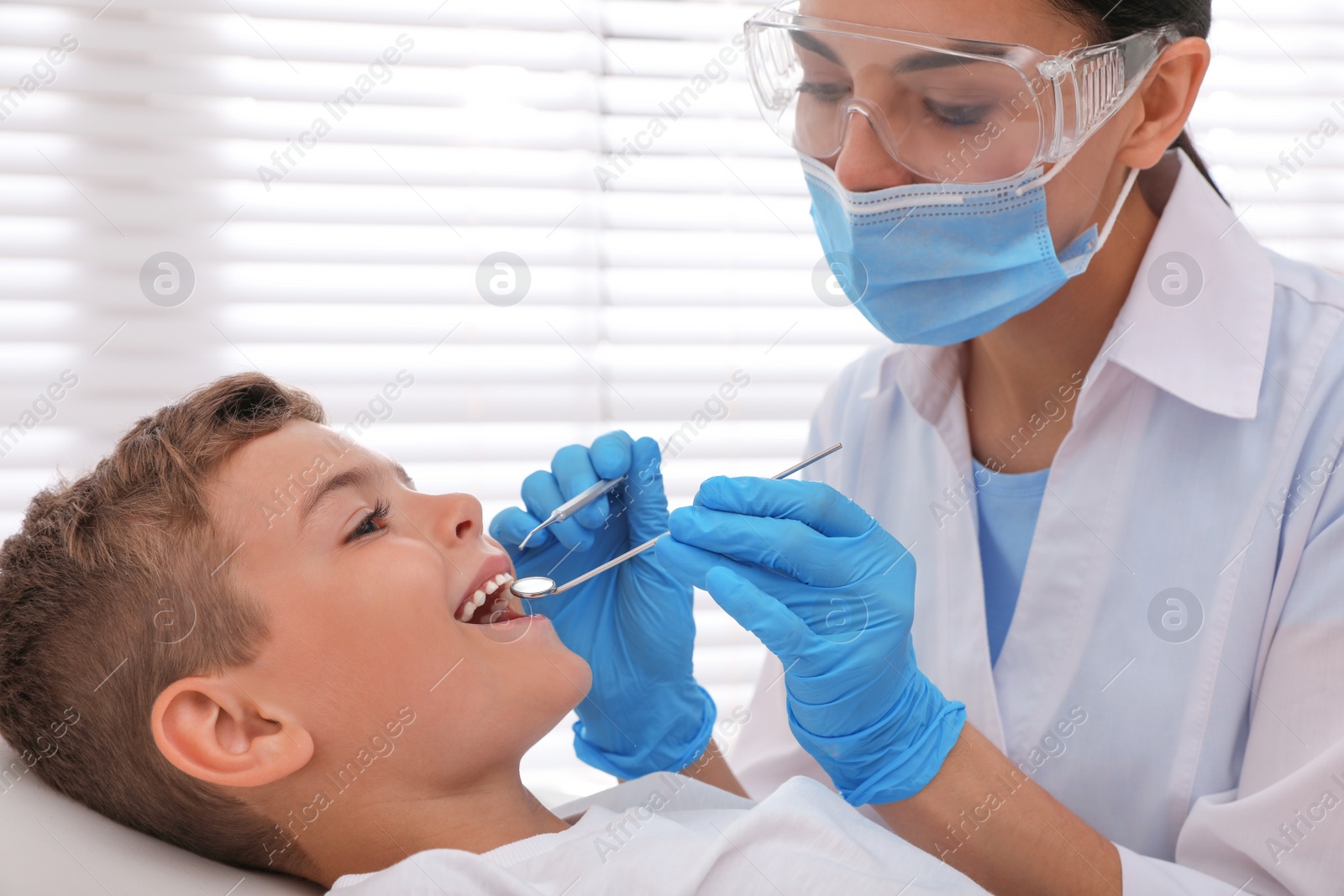 Photo of Dentist examining little boy's teeth in modern clinic