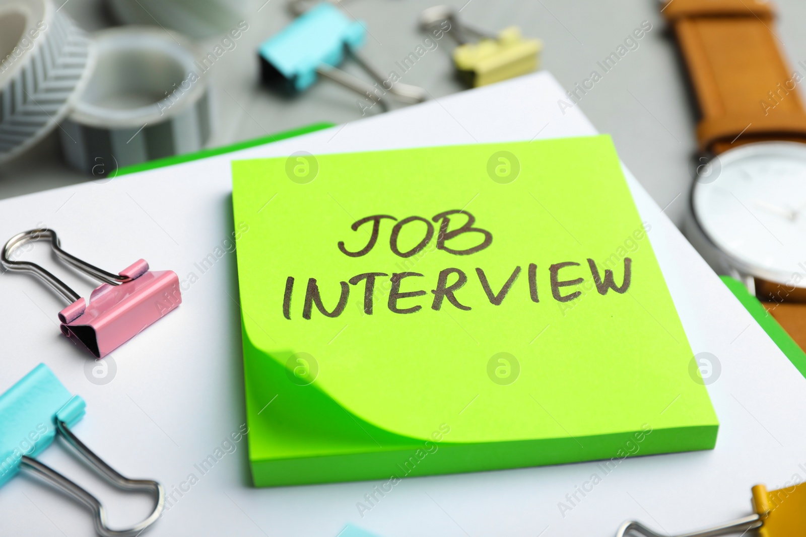 Photo of Reminder note about job interview and stationery on table, closeup