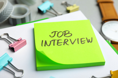 Reminder note about job interview and stationery on table, closeup