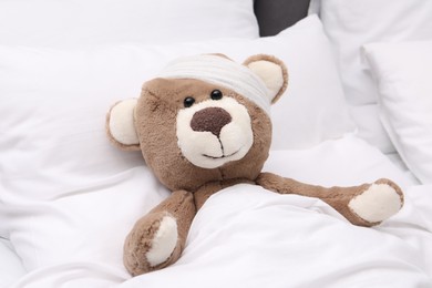 Toy cute bear with bandage under blanket in bed