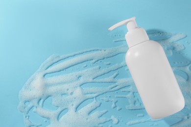 Bottle with cleansing foam on light blue background, top view. Cosmetic product