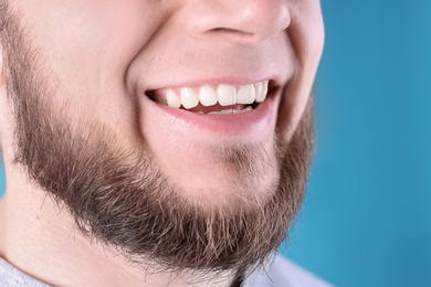 Photo of Young man with healthy teeth and beautiful smile on color background, closeup