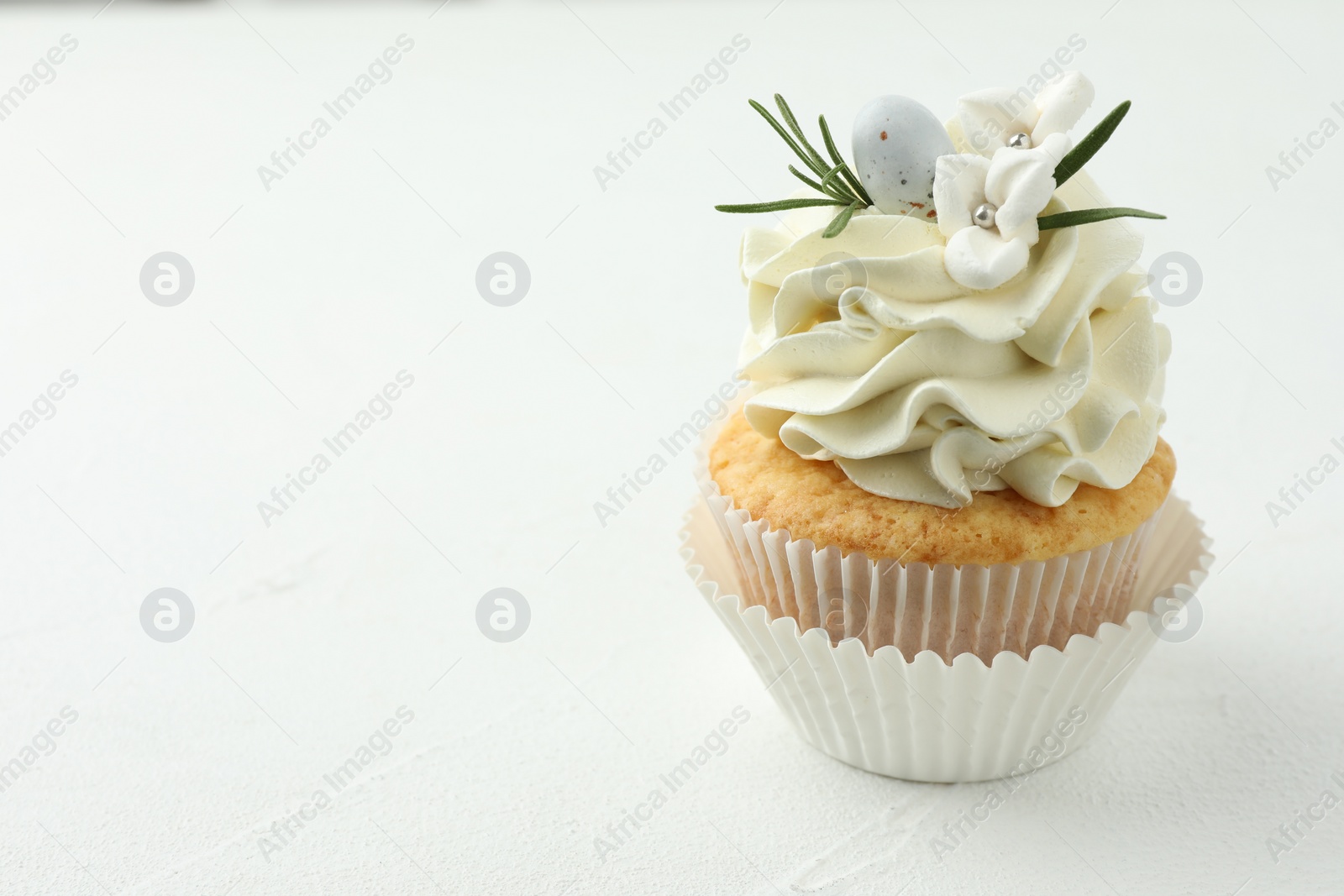 Photo of Tasty Easter cupcake with vanilla cream on white table, space for text