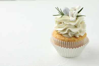 Photo of Tasty Easter cupcake with vanilla cream on white table, space for text