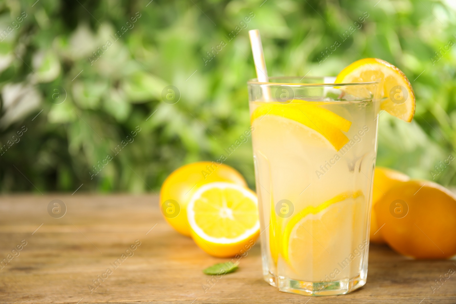 Photo of Cool freshly made lemonade in glass on wooden table. Space for text