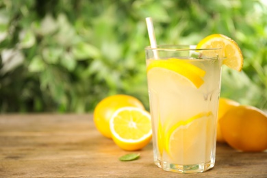 Cool freshly made lemonade in glass on wooden table. Space for text