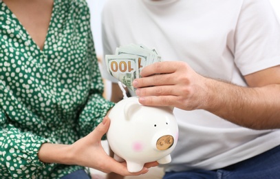 Photo of Young couple with piggy bank and money, closeup