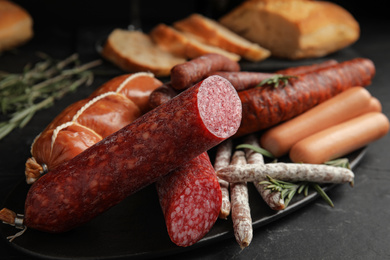 Different tasty sausages on black table, closeup