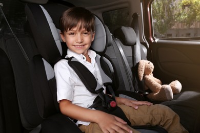 Photo of Little boy fastened with car safety belt in child seat