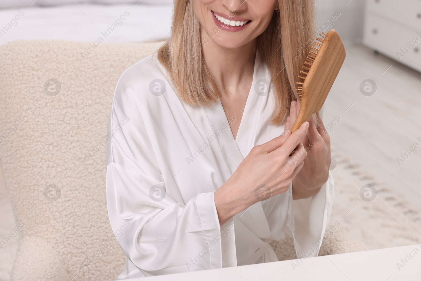 Photo of Woman brushing her hair indoors, closeup view