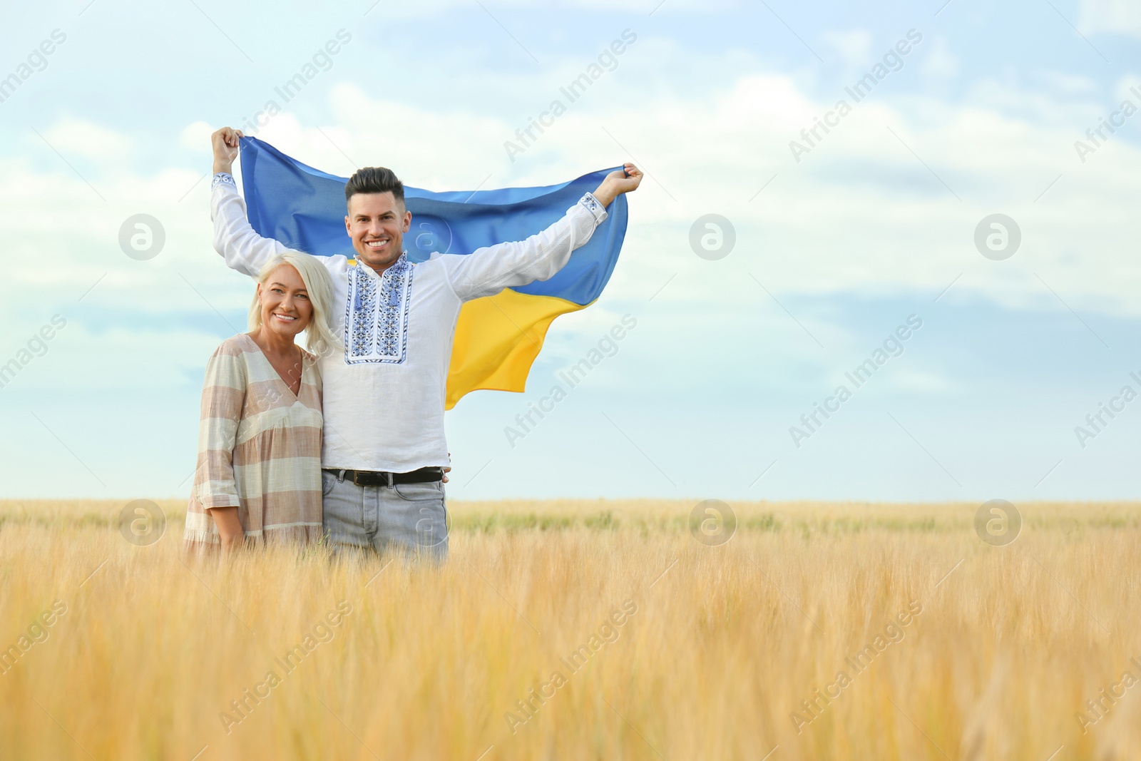 Photo of Man with mother holding national flag of Ukraine in field. Space for text