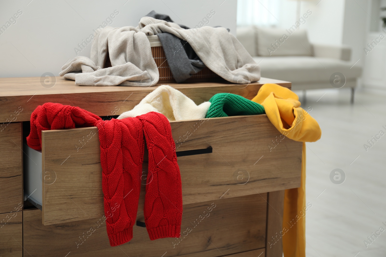 Photo of Cluttered chest of drawers indoors. Clothes in mess