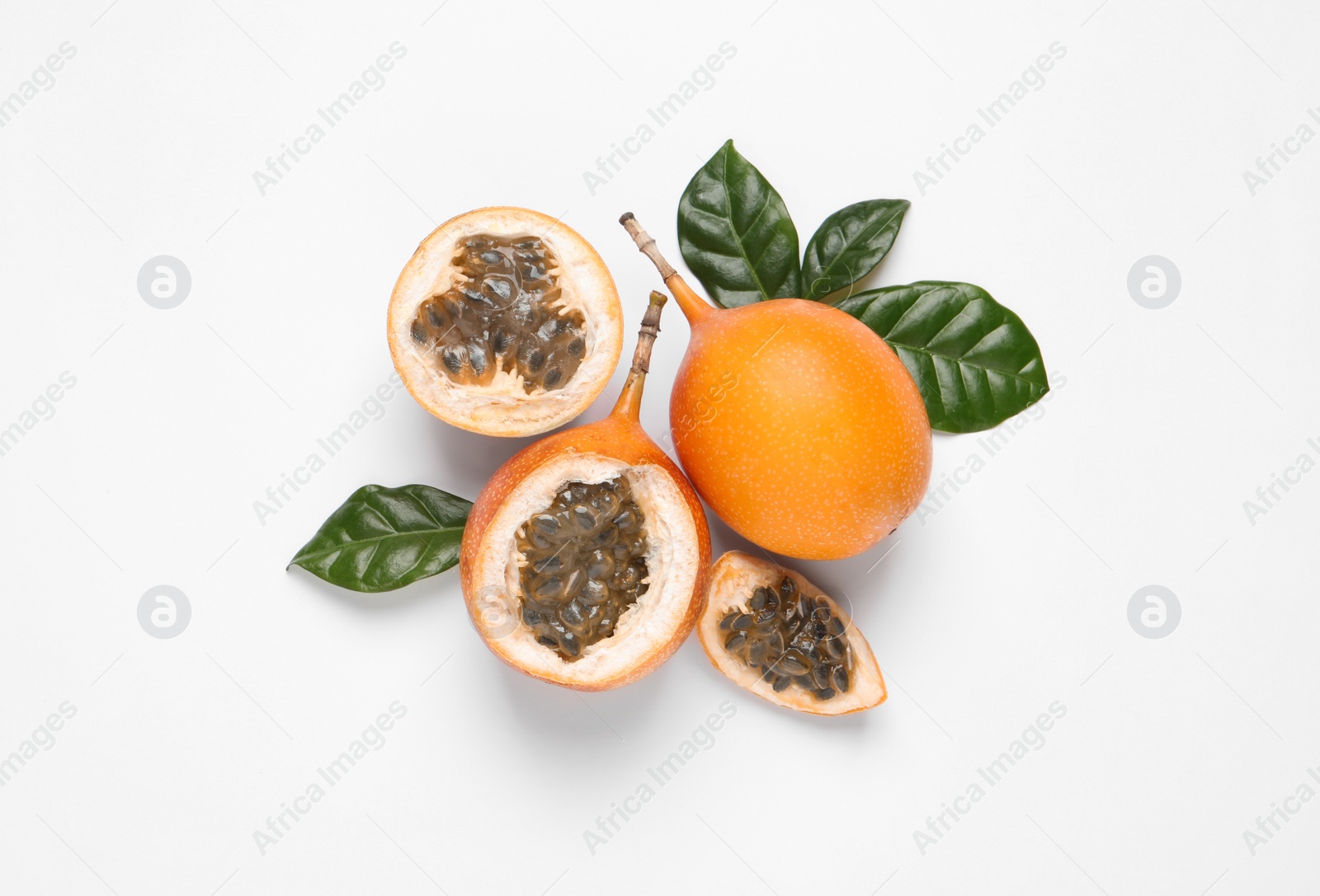 Photo of Delicious ripe granadillas with leaves on white background, flat lay