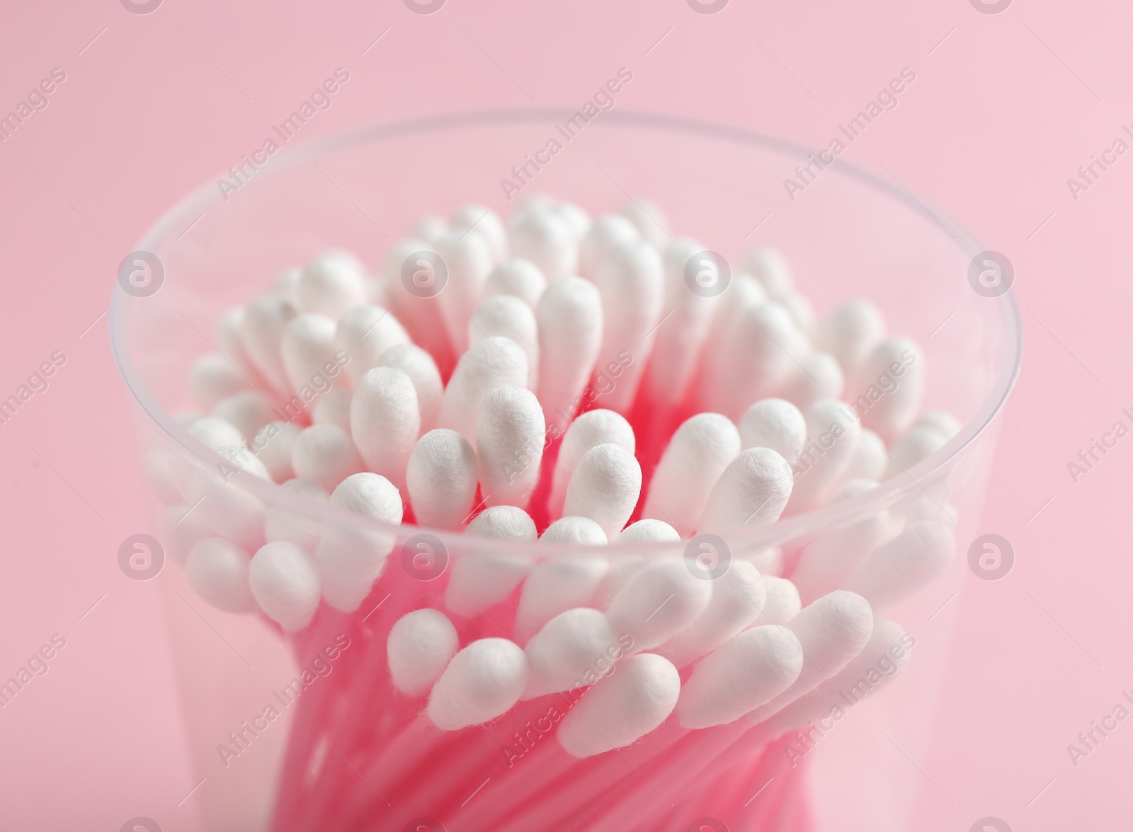 Photo of Plastic container with cotton swabs on color background, closeup