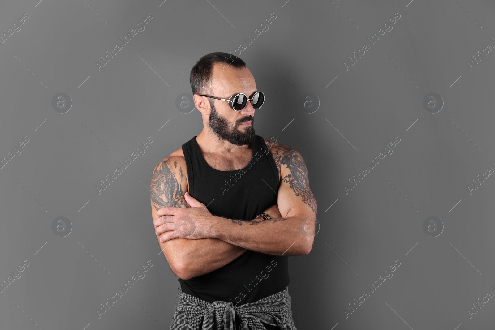 Photo of Portrait of handsome tattooed man on grey background