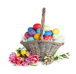 Wicker basket with bright painted Easter eggs and spring flowers on white background