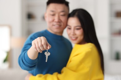 Happy couple with key in their new apartment, selective focus