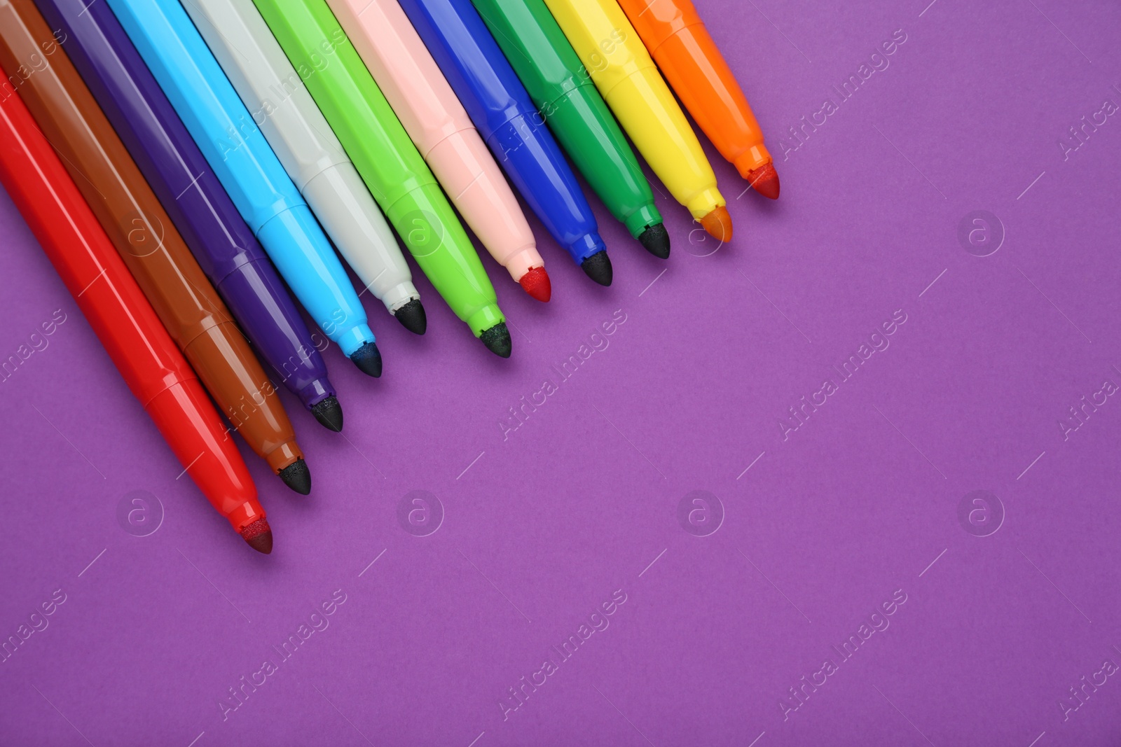 Photo of Different colorful markers on purple background, flat lay. Space for text