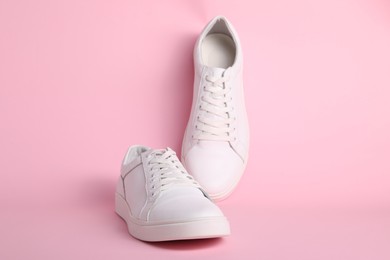 Photo of Pair of stylish white sneakers on pink background