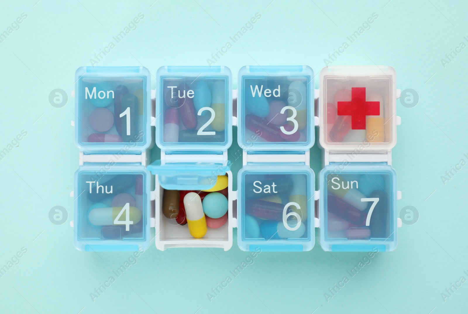 Photo of Pill box with medicaments on turquoise background, top view