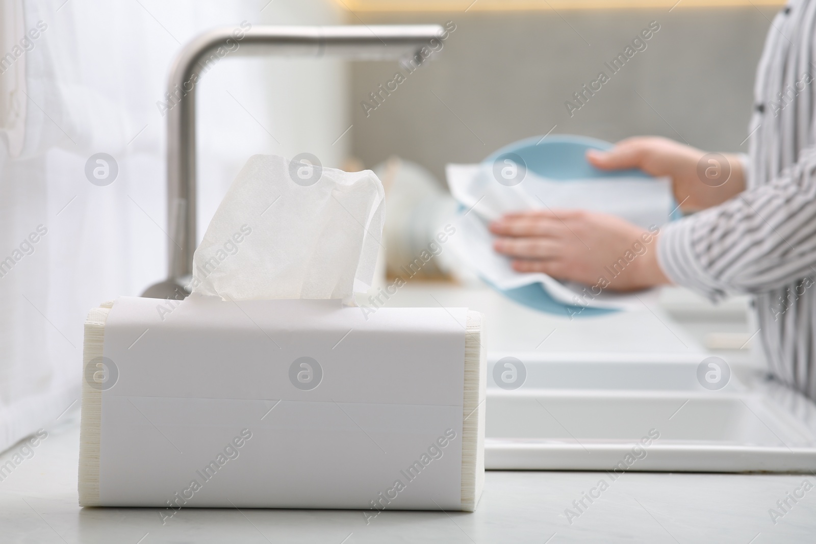 Photo of Woman wiping plate with paper towel above sink in kitchen, closeup. Space for text