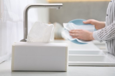 Woman wiping plate with paper towel above sink in kitchen, closeup. Space for text