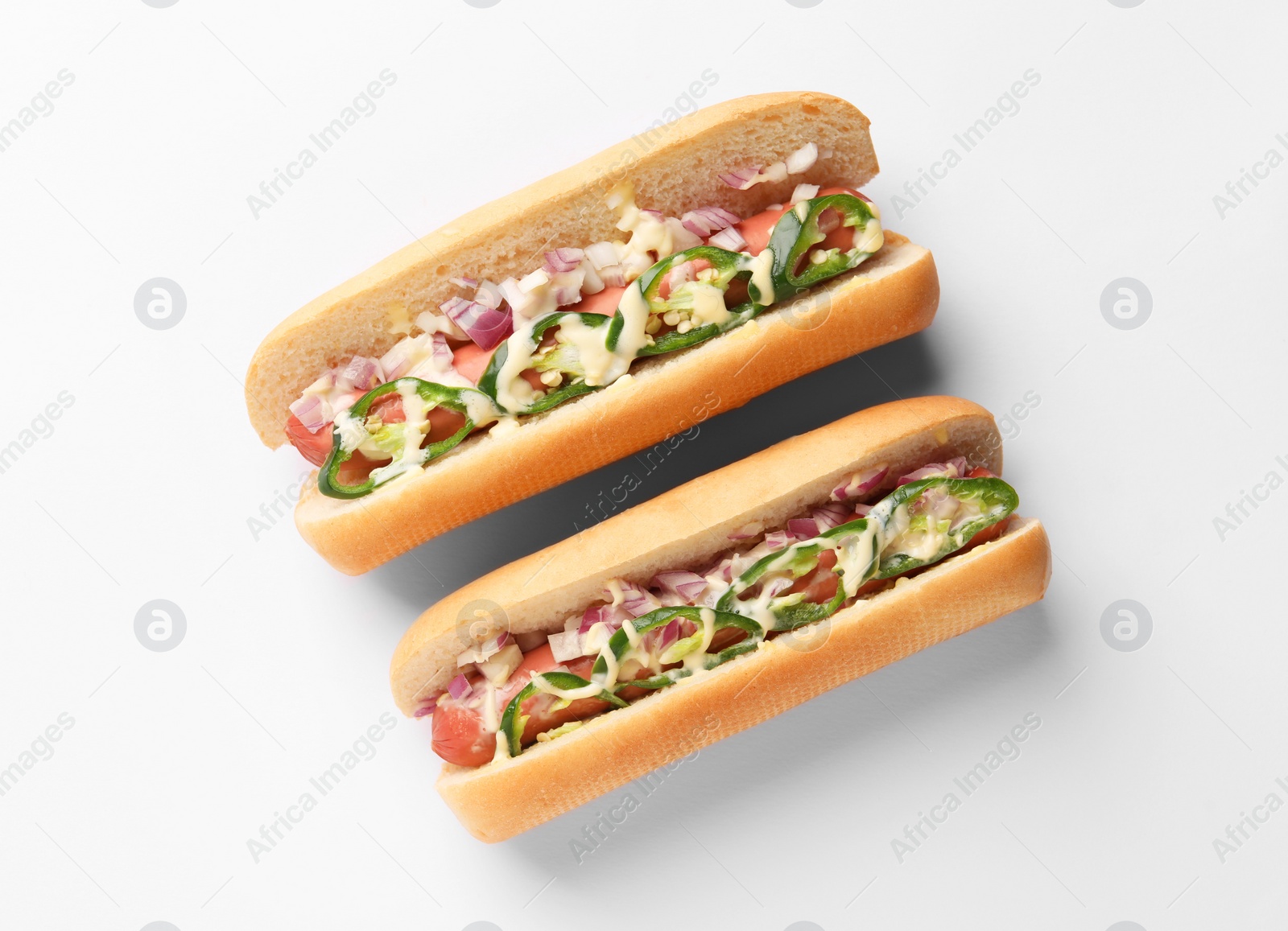 Photo of Delicious hot dogs with onion, chili pepper and sauce on white background, flat lay