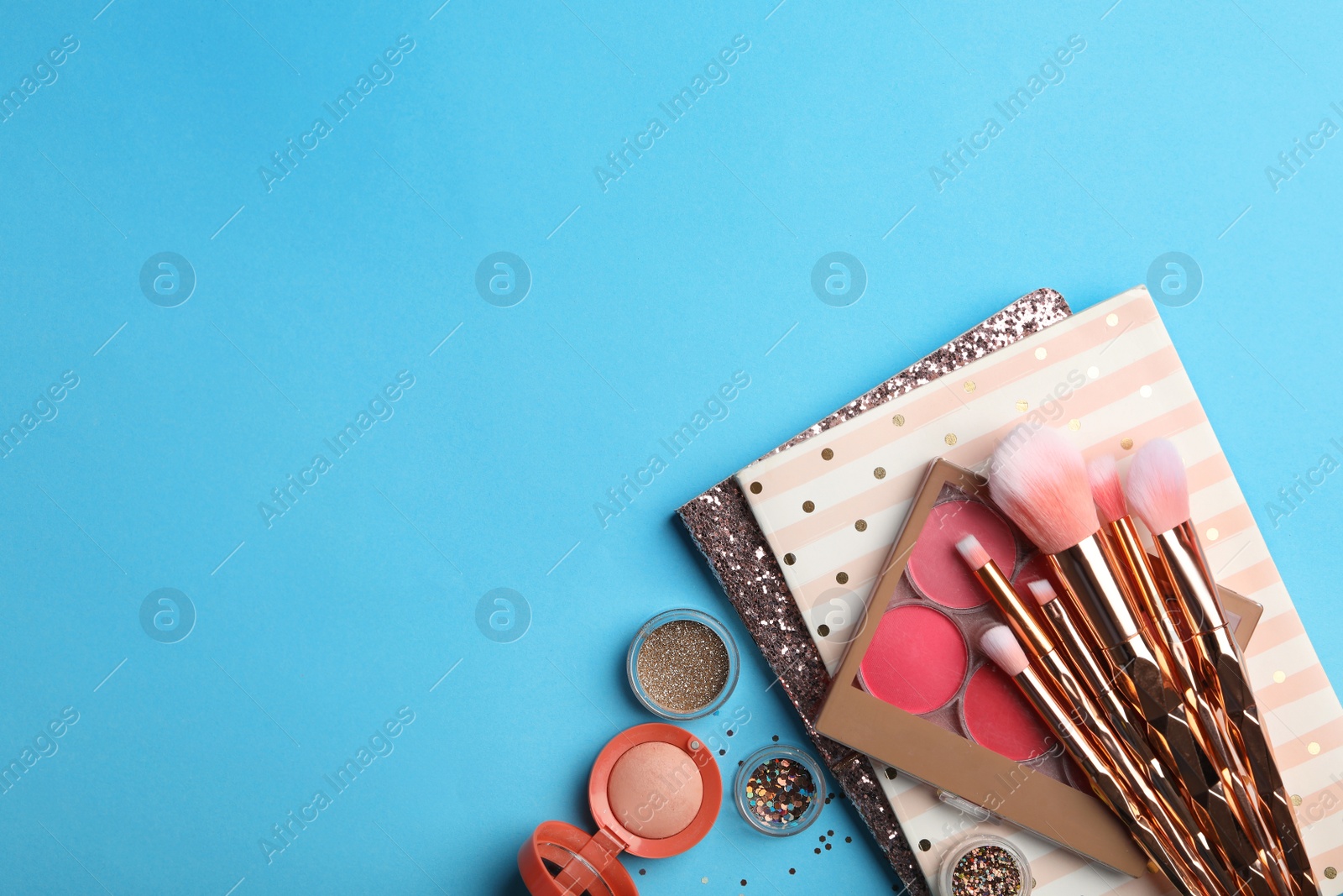 Photo of Flat lay composition with coral cosmetics and notebooks on light blue background. Space for text