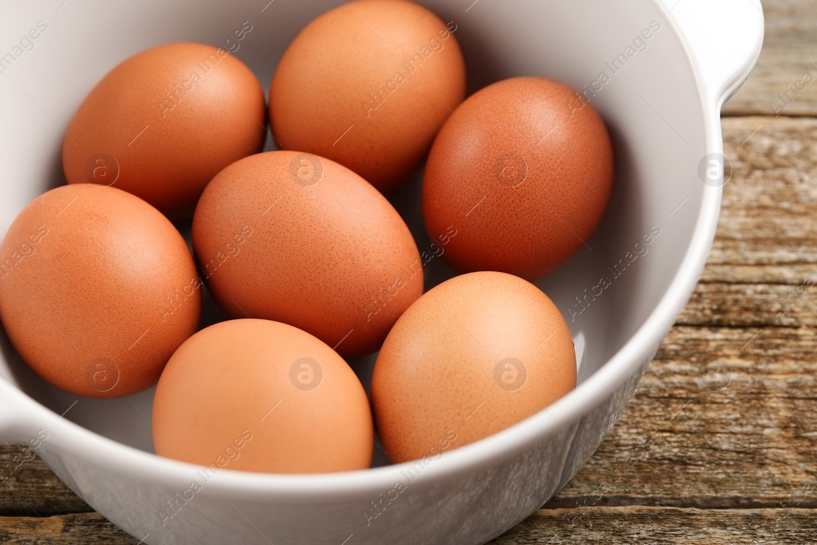 Photo of Unpeeled boiled eggs in saucepan on old wooden table, closeup