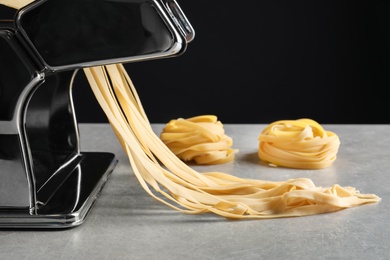 Photo of Pasta maker with dough on kitchen table