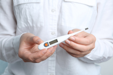 Photo of Woman holding modern digital thermometer, closeup view