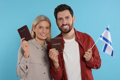 Photo of Immigration. Happy couple with passports and flag of Israel on light blue background