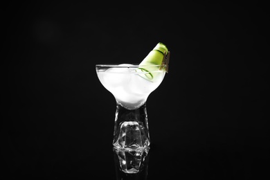 Photo of Glass of delicious cucumber martini with ice on dark background