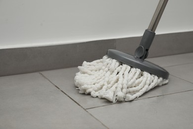 Photo of Cleaning grey tiled floor with string mop, closeup. Space for text