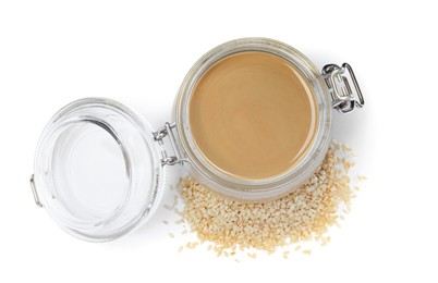 Photo of Tasty sesame paste in jar and seeds on white background, top view