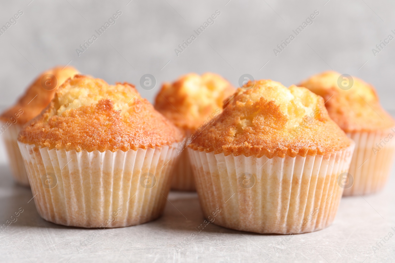 Photo of Tasty muffins on light grey table, closeup. Fresh pastry