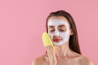 Young woman with face mask and sponge on pink background. Space for text