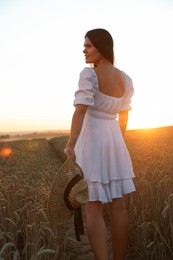 Photo of Beautiful young woman with straw hat in ripe wheat field at sunset