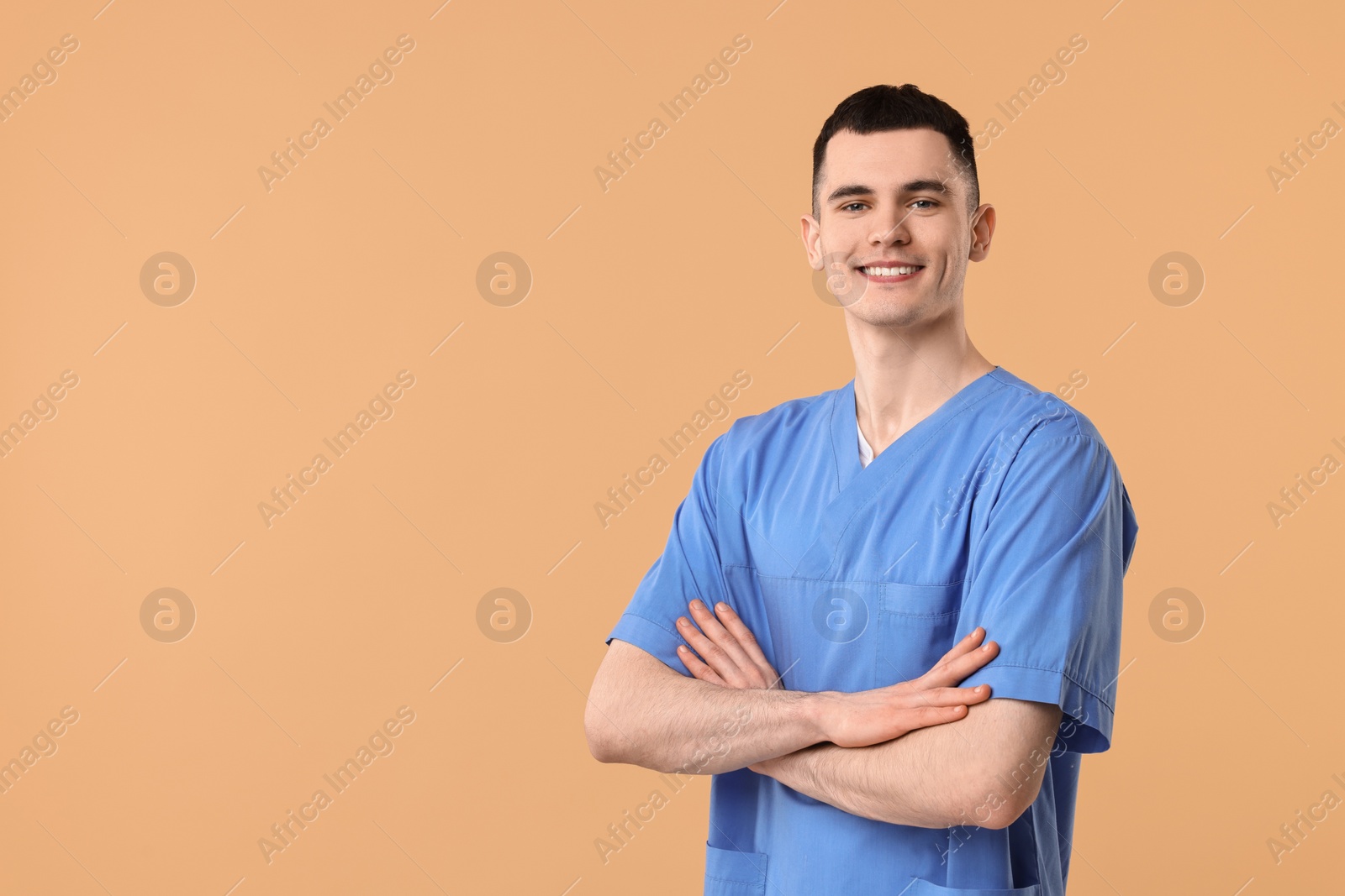 Photo of Portrait of smiling medical assistant with crossed arms on beige background. Space for text