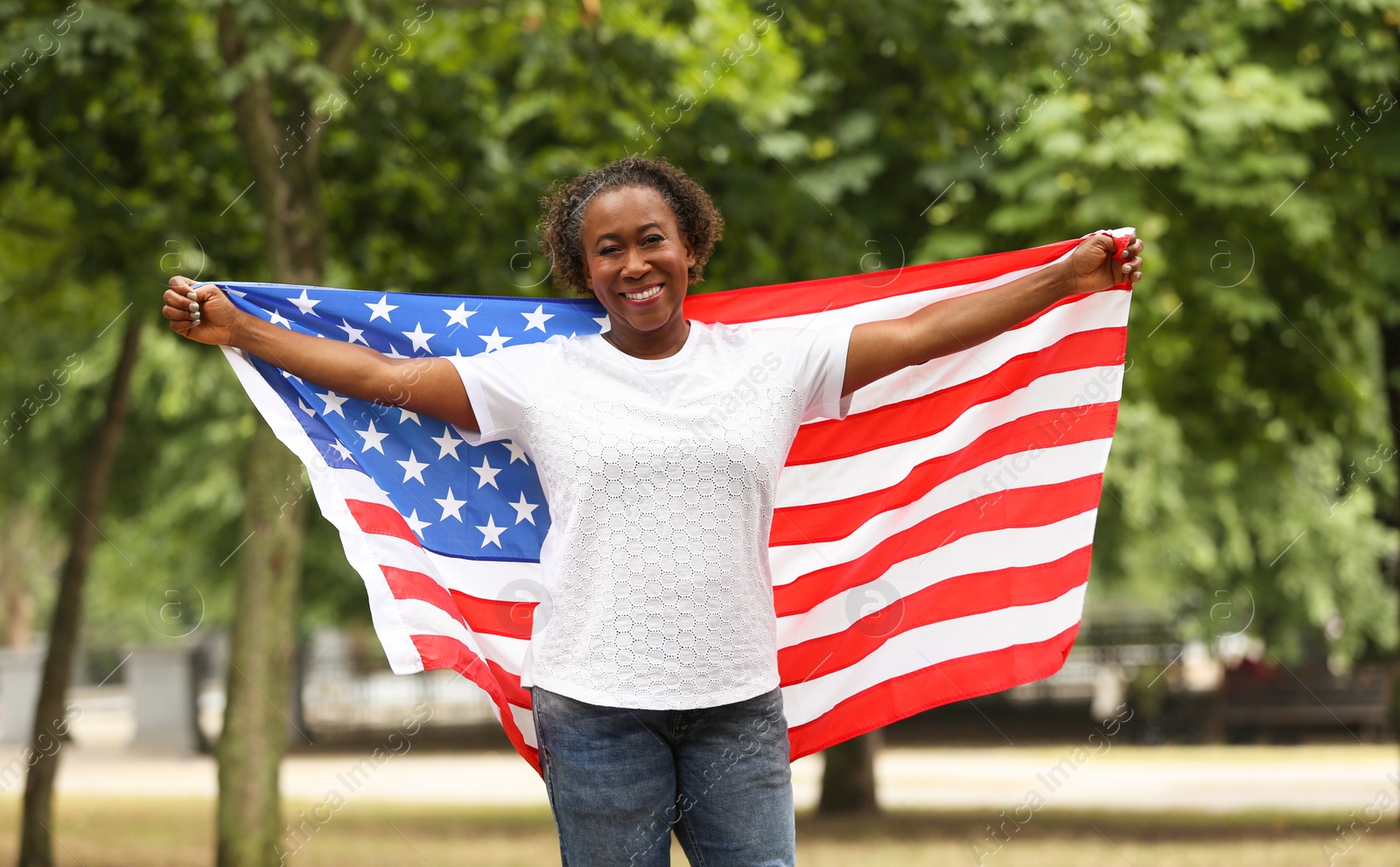 Photo of Portrait of happy African-American woman with USA flag in park
