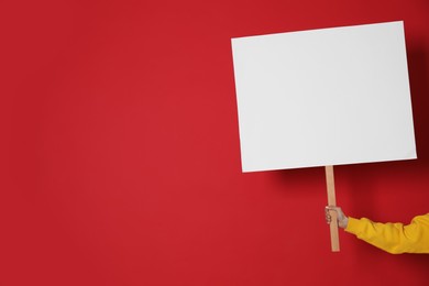 Woman holding blank sign on red background, closeup. Space for text