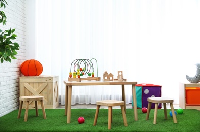 Stylish playroom interior with toys and modern wooden furniture