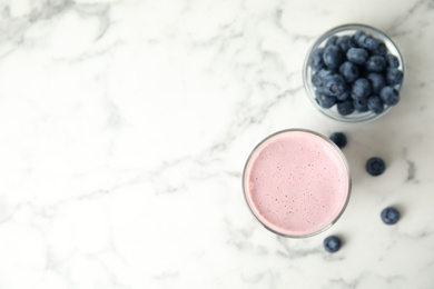 Photo of Tasty milk shake and blueberries on white marble table, flat lay. Space for text