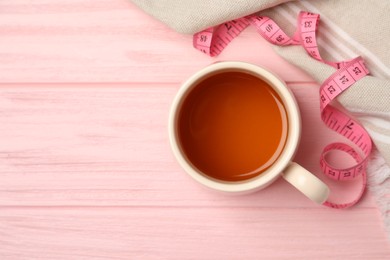 Photo of Flat lay composition with herbal diet tea and measuring tape on pink wooden table, space for text. Weight loss concept