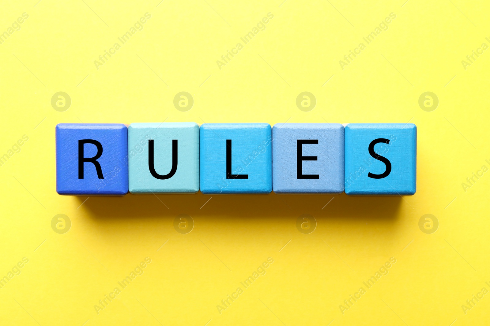 Photo of Word Rules made of wooden cubes with letters on yellow background