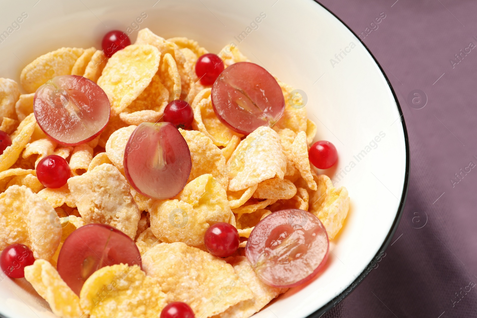 Photo of Corn flakes with berries on table, closeup. Healthy breakfast