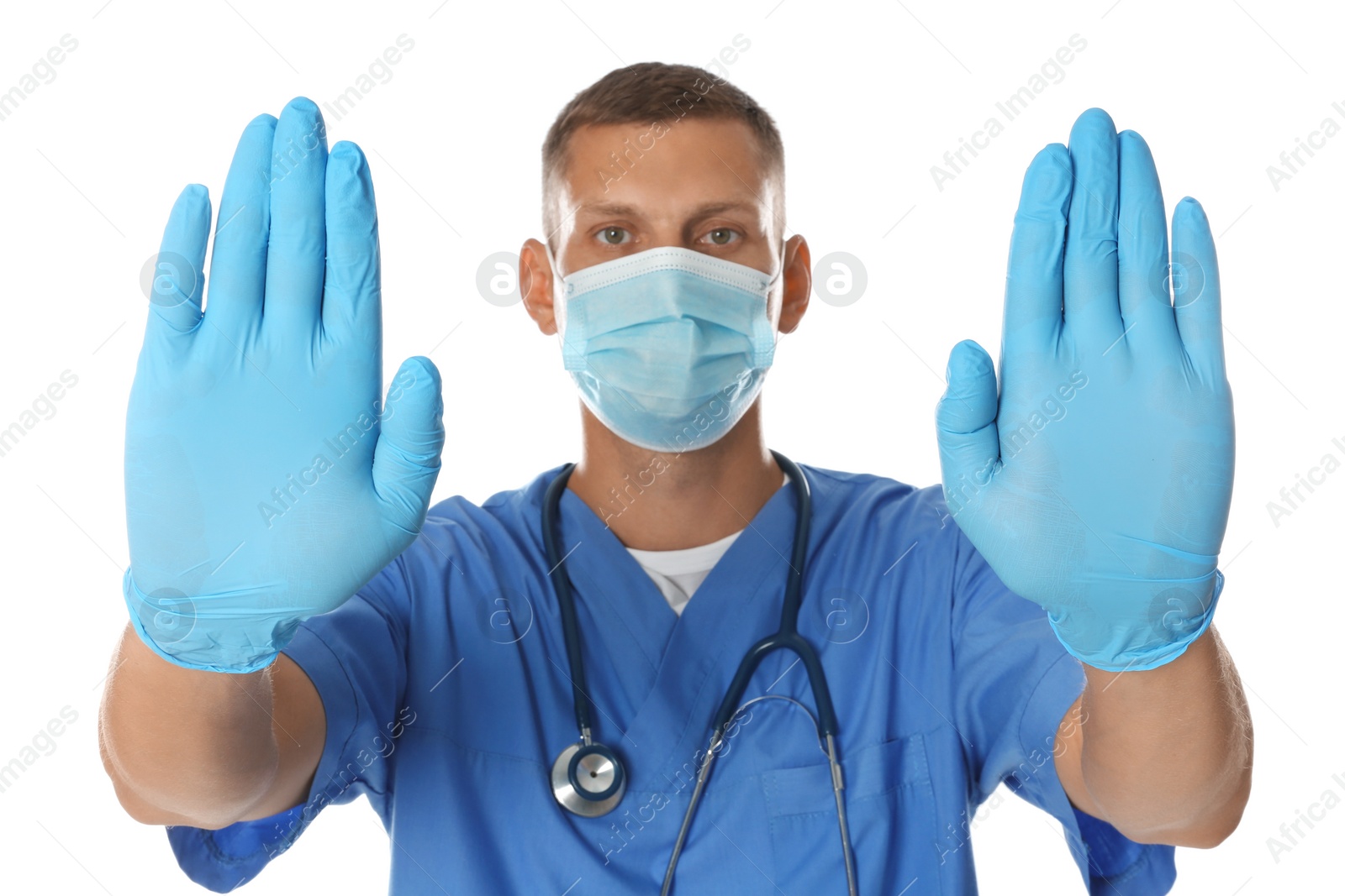 Photo of Doctor in protective mask showing stop gesture on white background. Prevent spreading of coronavirus