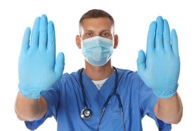 Photo of Doctor in protective mask showing stop gesture on white background. Prevent spreading of coronavirus