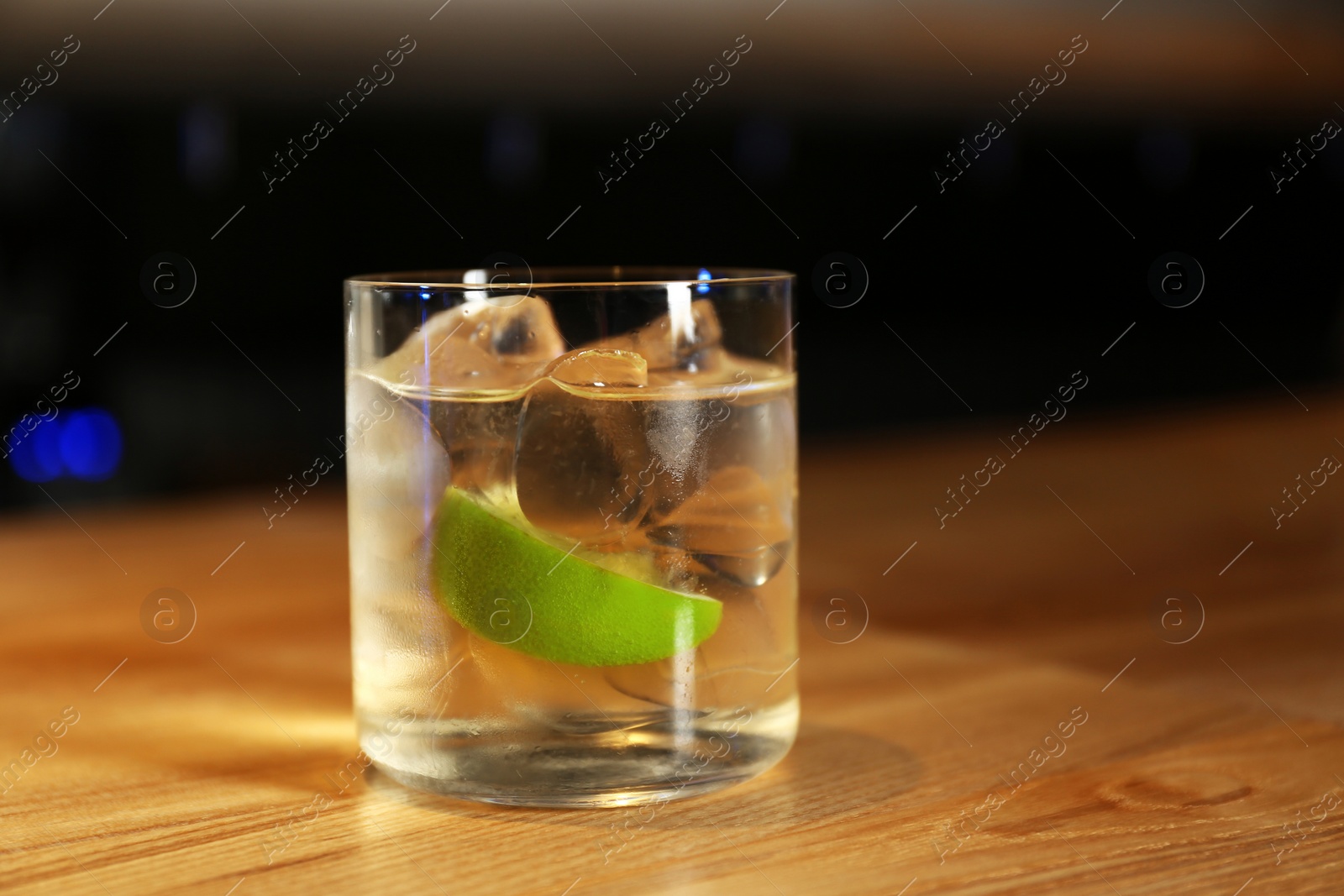Photo of Glass of delicious cocktail with vodka on wooden counter in bar