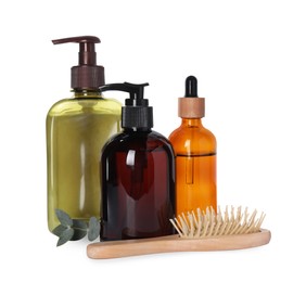 Different bottles of shampoo and wooden brush on white background